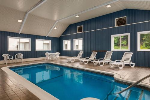 a swimming pool with lounge chairs and a table and a tablektop at Baymont by Wyndham Branford/New Haven in Branford