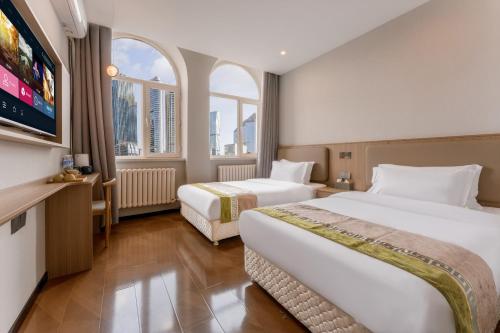 twee bedden in een hotelkamer met twee ramen bij Zhongmai Yunting Hotel in Harbin
