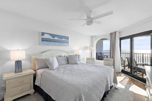 a white bedroom with a bed and a balcony at Seascape 315 - Oceanfront Condo Overlooking Pool in Isle of Palms