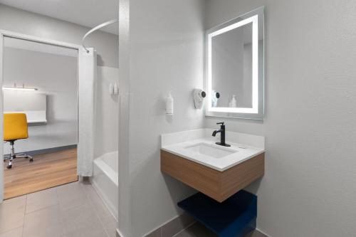 a white bathroom with a sink and a mirror at Microtel Inn & Suites by Wyndham Sioux Falls in Sioux Falls