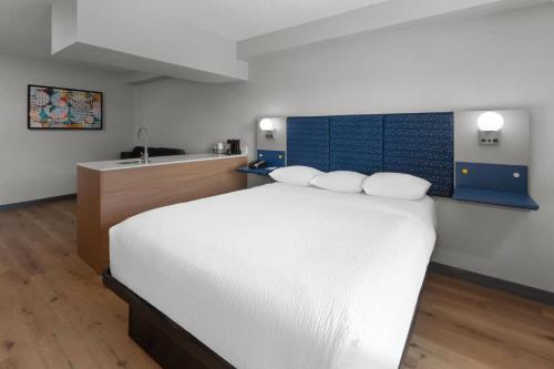 a bedroom with a white bed and a sink at Microtel Inn & Suites by Wyndham Sioux Falls in Sioux Falls