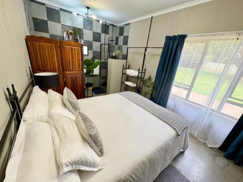 a bedroom with a large bed with pillows and a window at Stylish One Bedroom Garden Suite in Polokwane