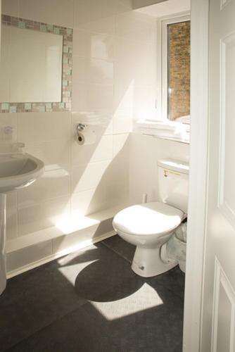 a white bathroom with a toilet and a sink at The Guest House Broadstairs in Broadstairs