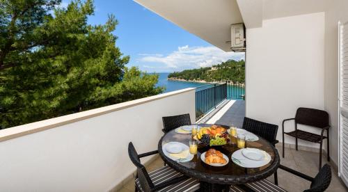 a table with food on a balcony with a view of the water at Apartments Domani in Omiš