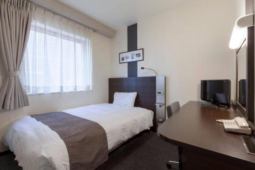 a hotel room with a bed and a desk with a computer at Comfort Hotel Sendai East in Sendai