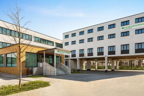 a large white building with a tree in front of it at Wyndham Garden Munich Messe in Munich
