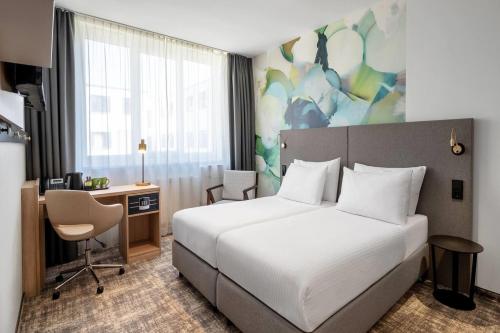 a bedroom with a bed and a desk and a computer at Wyndham Garden Munich Messe in Munich
