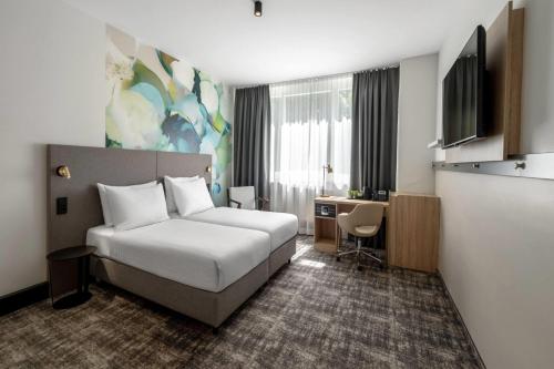a hotel room with a bed and a desk at Wyndham Garden Munich Messe in Munich