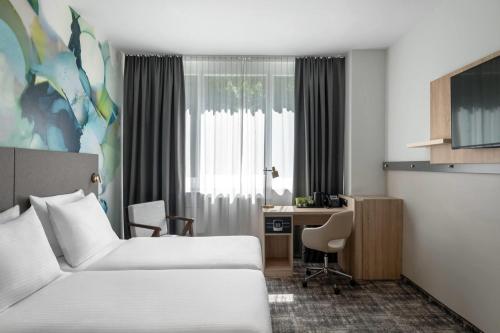 a hotel room with two beds and a desk at Wyndham Garden Munich Messe in Munich