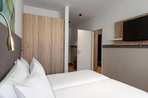 a bedroom with a white bed with a flat screen tv at Wyndham Garden Munich Messe in Munich