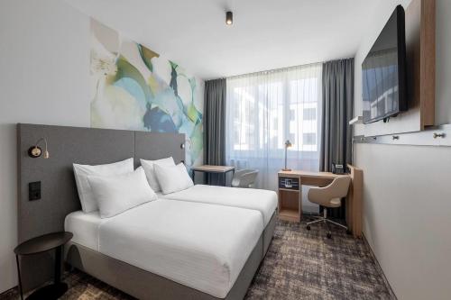 a hotel room with a bed and a desk at Wyndham Garden Munich Messe in Munich