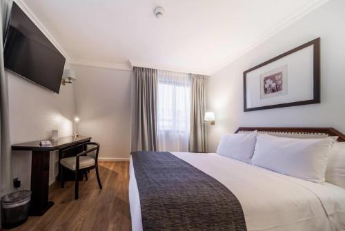 a hotel room with a bed and a desk at Wyndham Garden Santiago Kennedy in Santiago