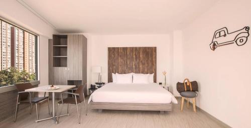 a bedroom with a bed and a table and a desk at V Grand Hotel, a member of Radisson Individuals in Medellín