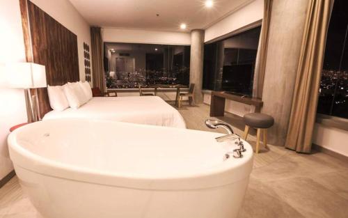 a bathroom with a bath tub and a bed and a bed and a room with at V Grand Hotel, a member of Radisson Individuals in Medellín