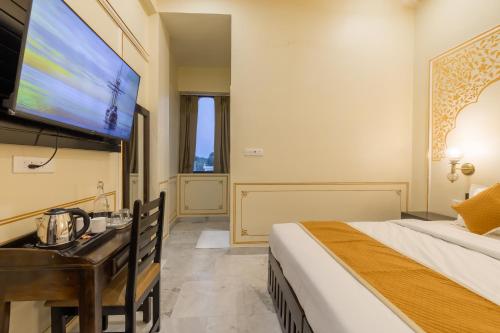 a bedroom with a bed and a desk and a tv at Umrao Mahal Jaipur in Jaipur