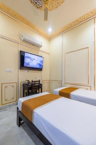 a hotel room with two beds and a flat screen tv at Umrao Mahal Jaipur in Jaipur
