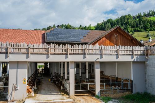 a barn with solar panels on the roof at Garnì Iosc in San Vigilio Di Marebbe