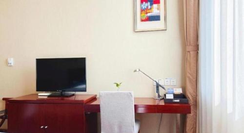 a room with a desk with a television on it at Qingdao Blue Horizon Hotel Licang in Qingdao