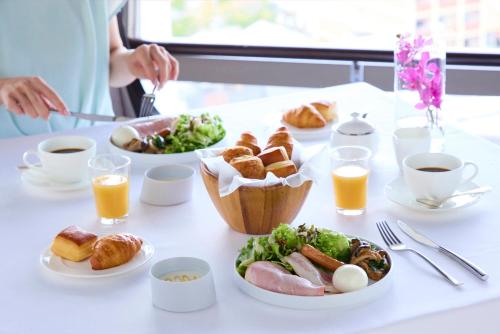 a table with plates of food and cups of orange juice at RIHGA Royal Hotel Kyoto in Kyoto