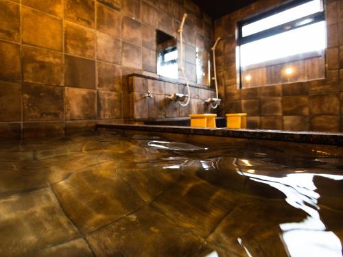 Un baño con bañera, lavabo y espejo. en Kurosakisou, en Miyazu