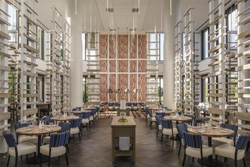 a restaurant with tables and chairs in a room with tall ceilings at Hyatt Regency Grand Cypress Resort - Free Shuttle to Theme Parks! in Orlando