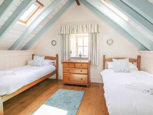 a attic bedroom with two beds and a window at Dovecote in Saint Goran