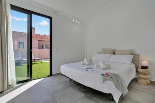 a bedroom with a white bed and a large window at Golden dunes villa shakespeare in Caleta De Fuste