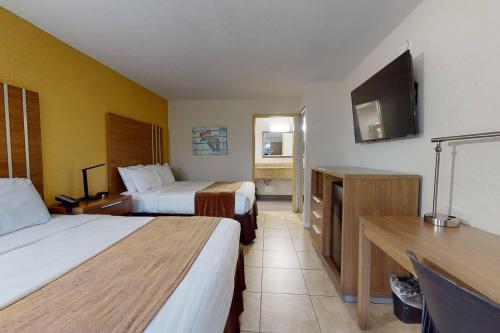 a hotel room with two beds and a flat screen tv at Rodeway Inn & Suites Fort Lauderdale Airport & Cruise Port in Fort Lauderdale