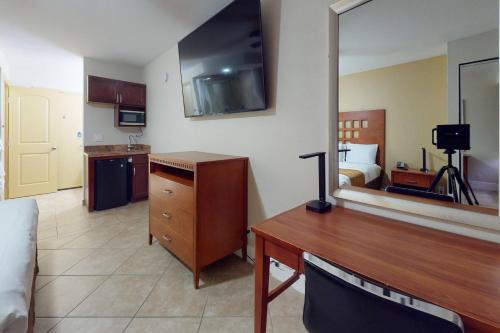 a hotel room with a desk and a bedroom at Rodeway Inn & Suites Fort Lauderdale Airport & Cruise Port in Fort Lauderdale