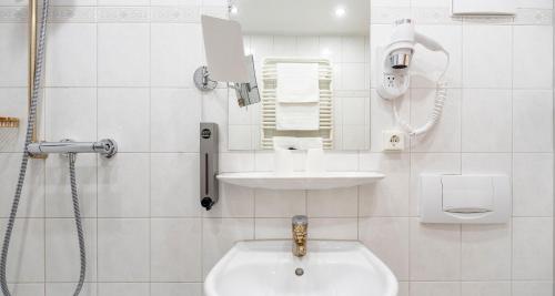 a white bathroom with a sink and a shower at PLAZA Hotel Buchhorner Hof in Friedrichshafen
