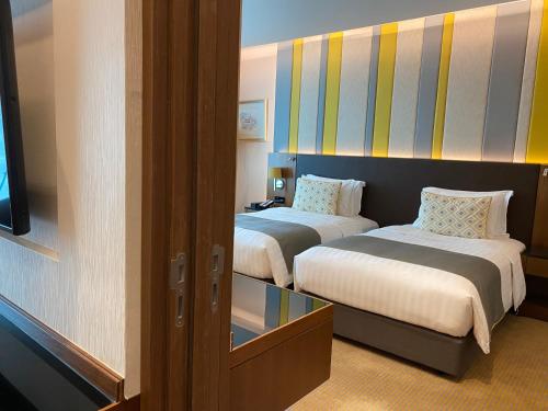 a room with two beds and a mirror at Lancaster Bangkok in Bangkok