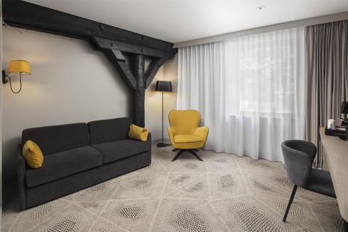 a living room with a couch and a yellow chair at Hilton Garden Inn Paris La Villette in Paris