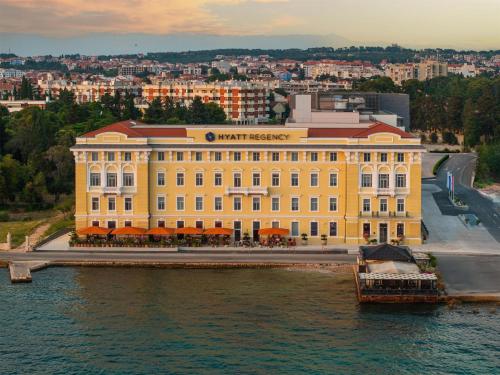 a large yellow building on the water next to a river at Hyatt Regency Zadar in Zadar