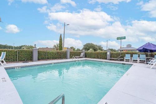 a swimming pool at a resort with chairs and a fence at Quality Inn Prattville I-65 in Prattville