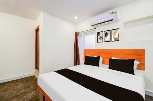 a bedroom with a white bed with black pillows at Collection O Neredmet Road in Hyderabad