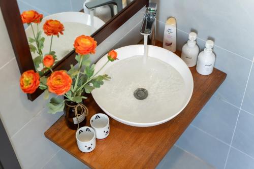 a bathroom sink with orange flowers and a mirror at Sanh Homestay in Hue