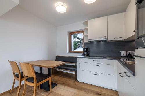 a kitchen with white cabinets and a wooden table at Schwarzhans Appartments in Bludenz