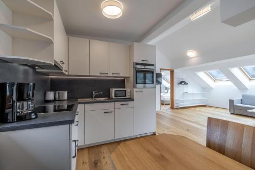an open kitchen with white cabinets and a living room at Schwarzhans Appartments in Bludenz