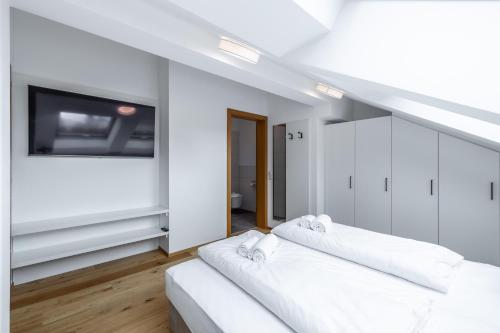 a white room with two beds and a flat screen tv at Schwarzhans Appartments in Bludenz