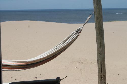 a hammock sitting on a beach next to the ocean at Arenas del Mar in Punta Del Diablo