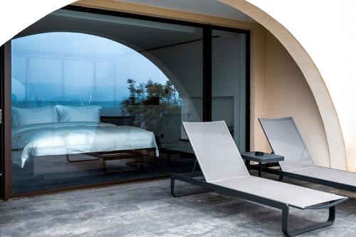 a bedroom with a bed and two chairs in a room at Mont XIX Villa - Panoramic Sea & Mountain View in Dali Airport