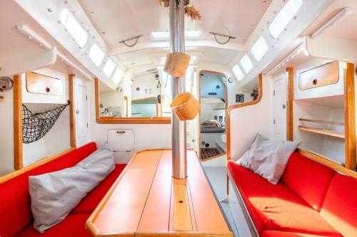 a train room with a red couch and a table at Voilier Pyman - Le Chant Des Voiles in Douarnenez