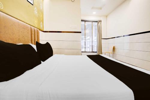 a bedroom with a large white bed with black pillows at Collection O Mumbai-Ahmedabad Highway in Mumbai