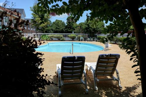 two chairs sitting in front of a swimming pool at Country Inn & Suites by Radisson, Charlotte I-85 Airport, NC in Charlotte