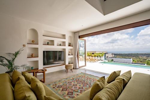 a living room with a couch and a large window at La Concha Bingin in Bingin Beach