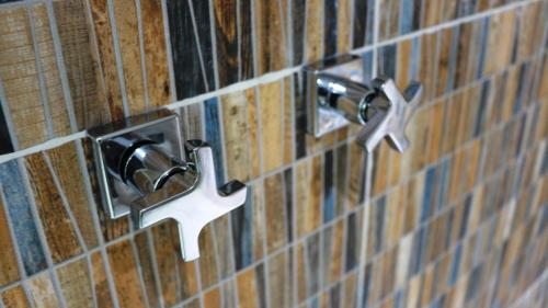 a bathroom with two faucets on a tiled wall at Pousada La Dolce Vita in Búzios
