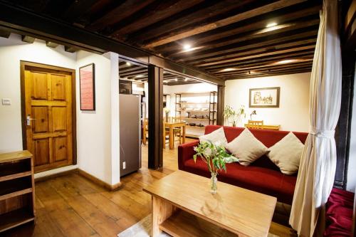 a living room with a red couch and a table at The Newari dream in Old Patan-high ceiling & charm in Pātan