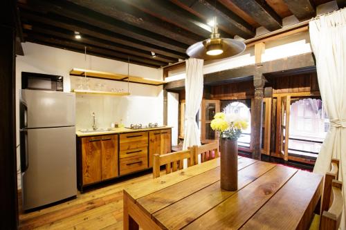 a kitchen with a wooden table and a refrigerator at The Newari dream in Old Patan-high ceiling & charm in Pātan