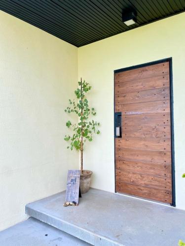 a wooden door with a potted tree next to a building at 오를 Orle in Kama-ri