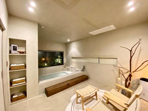 a bathroom with a tub and a television and chairs at 오를 Orle in Kama-ri